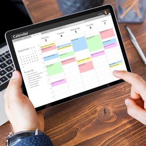 Person using a digital calendar on a tablet, showing scheduled appointments and to-do list.