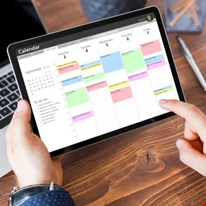 Person using a digital calendar on a tablet, showing scheduled appointments and to-do list.