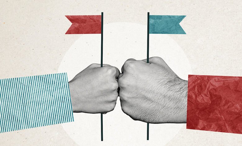 Two fists bumping, each holding a small flag representing opposing political parties.