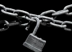 Close-up of a rusty chain and open padlock against a black background.