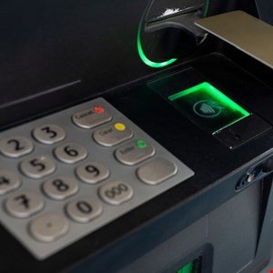 Close-up of an ATM machine keypad and card slot with a green light.