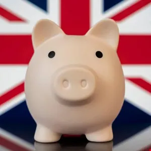 Pink piggy bank in front of a blurred Union Jack flag background.