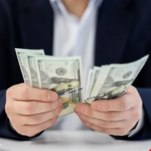 Close-up of hands holding and counting US dollar bills.