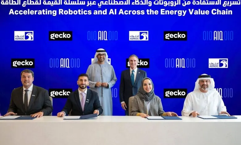 Group signing agreement with ADNOC, Gecko, and AIQ logos in background.