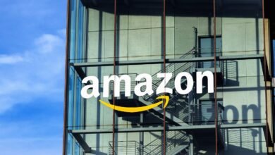 The Amazon logo with its signature smile is displayed on the glass facade of a modern building.