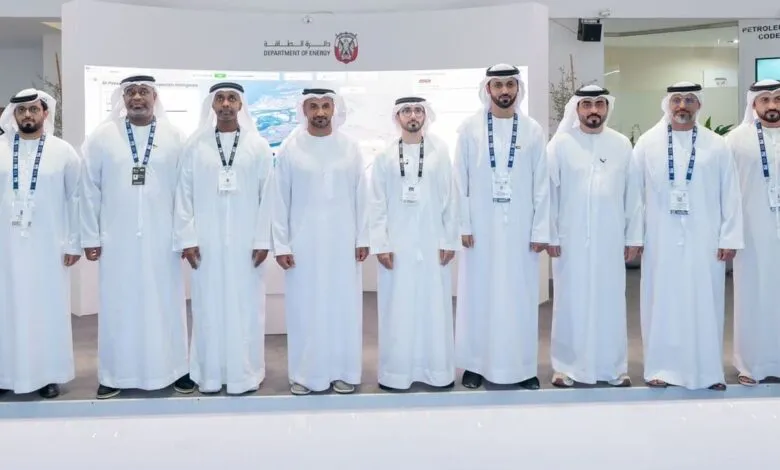 Group of men in traditional white Emirati clothing standing in front of a screen displaying energy data.