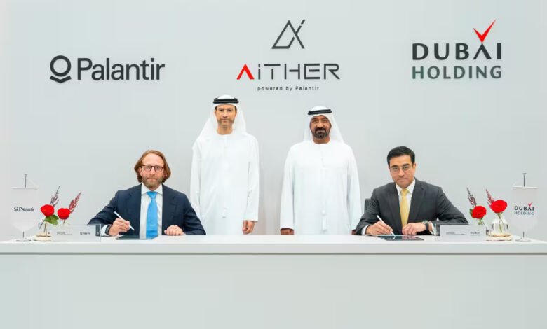 Four men in formal attire and traditional Emirati dress signing a document at a table.