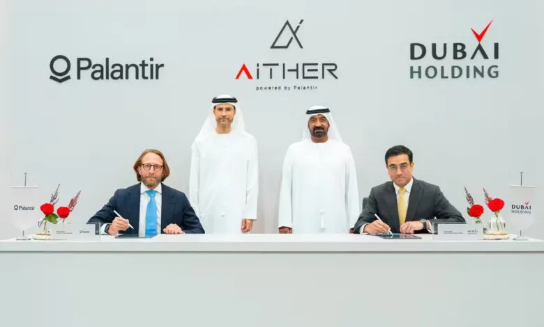 Four men in formal attire and traditional Emirati dress signing a document at a table.