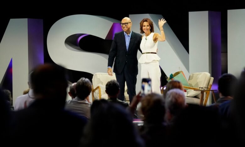 Ali Velshi and Stephanie Ruhle wave to an audience on stage with MSNBC logo.