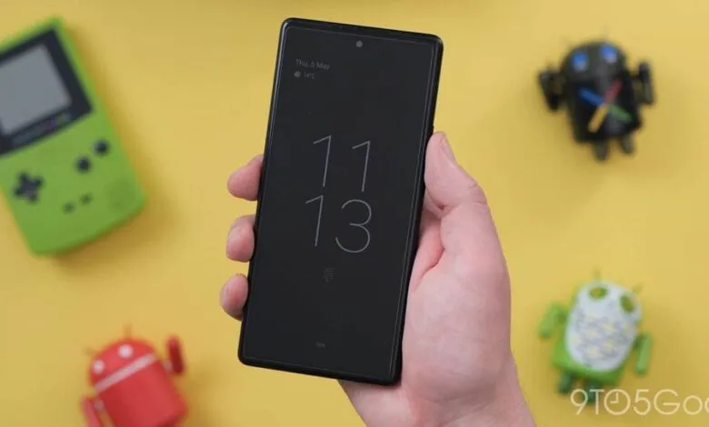 Hand holding a black smartphone displaying the time and date on its always-on display.