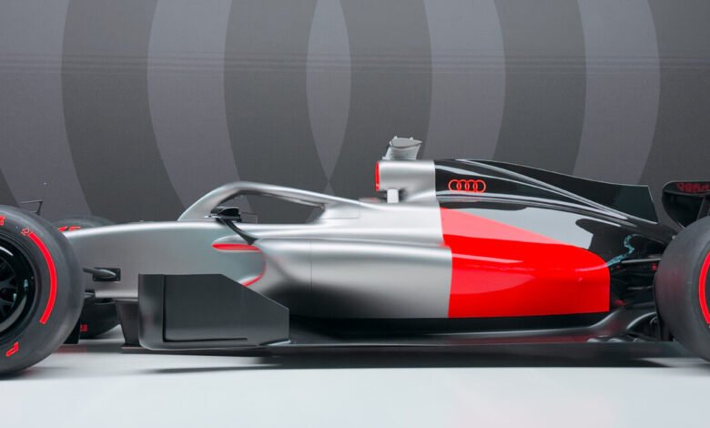 Side profile of an Audi Formula 1 race car with a silver and red livery.