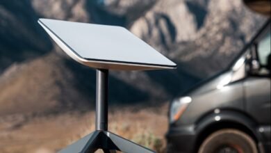 A white Starlink satellite dish on a tripod in a remote, mountainous landscape.