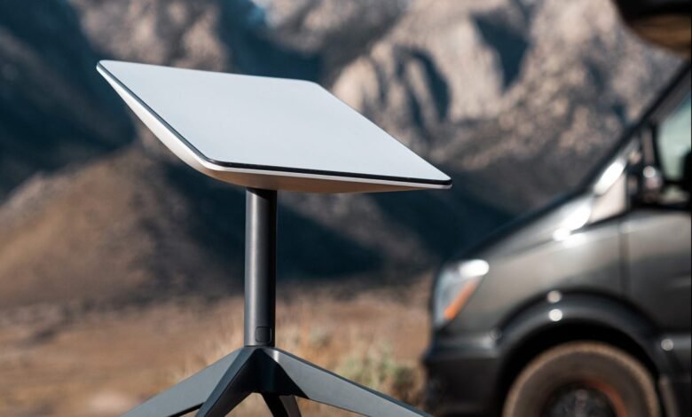 A white Starlink satellite dish on a tripod in a remote, mountainous landscape.