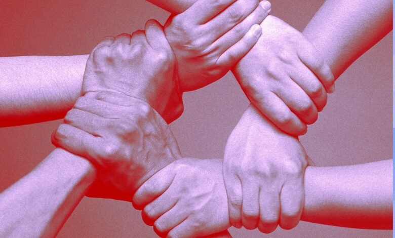 Close-up of four hands linked together in a circle, symbolizing unity and teamwork.