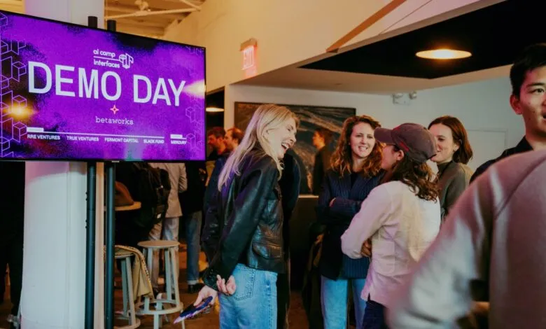People networking at Betaworks AI Camp Demo Day event with a large screen displaying event details.