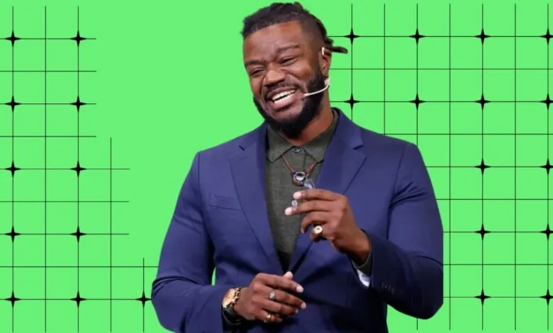Man in suit smiles against a green grid background.