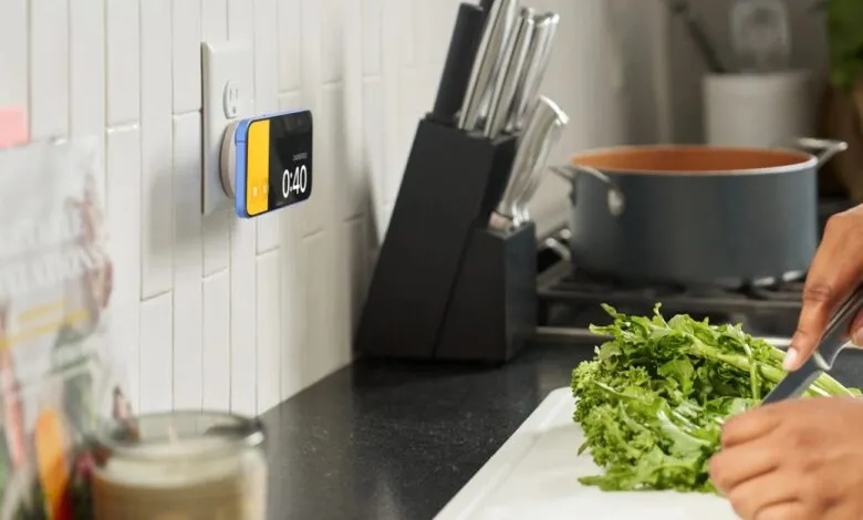 Smart display plugged into outlet showing timer while person preps food.