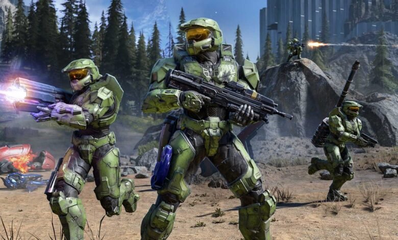 Master Chief and other Spartans in combat on a rocky, forested terrain.