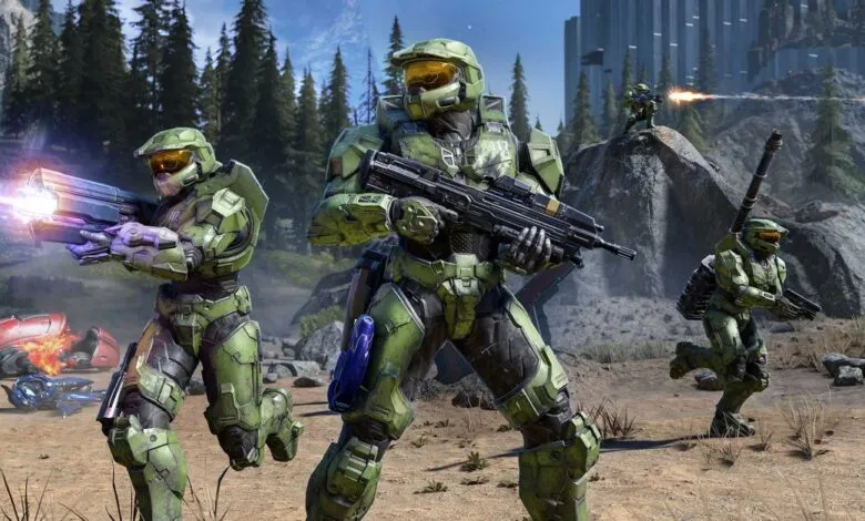 Master Chief and other Spartans in combat on a rocky, forested terrain.