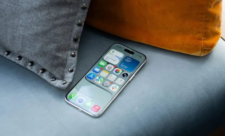 A modern smartphone with a colorful app interface rests on a blue upholstered surface.