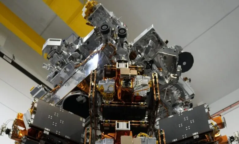 Complex spacecraft module with metallic panels and intricate wiring, viewed from below.