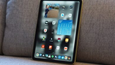 Gold iPad Mini on gray fabric showing apps and widgets.