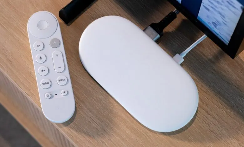 White Google Chromecast with Google TV remote and streaming device on a wooden surface