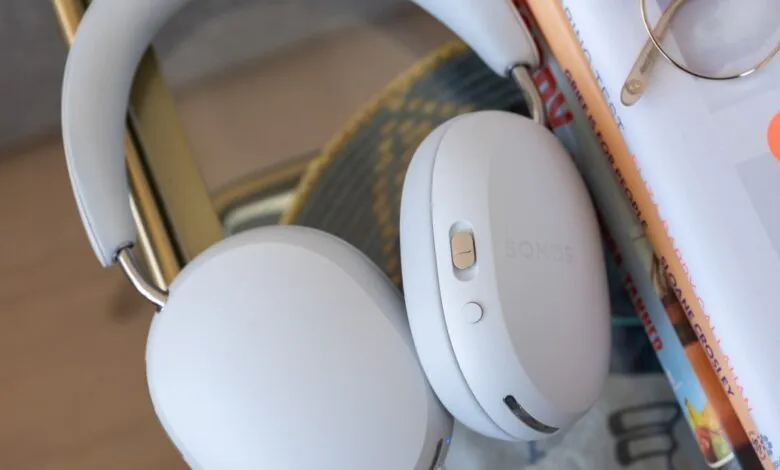 White Sonos headphones resting on books and glasses, close-up shot.