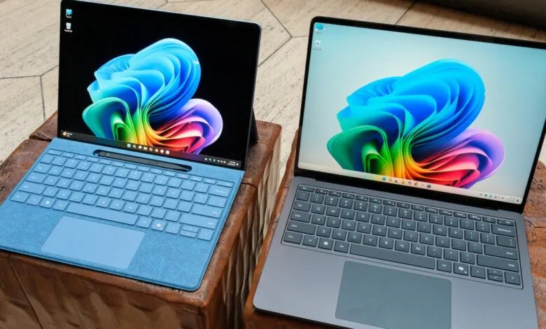 Two laptops, one blue and one gray, displaying colorful abstract wallpapers.
