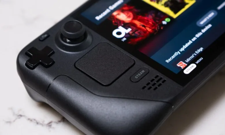Close-up of a black Steam Deck handheld gaming console with its screen displaying game art.