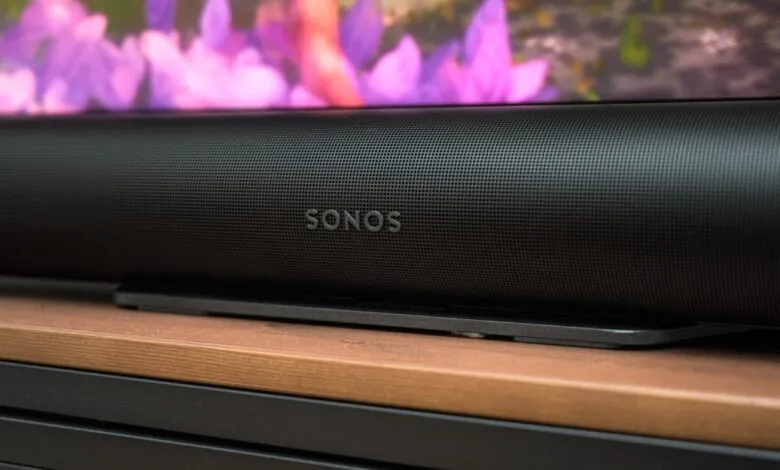 Close-up of a black Sonos soundbar with the logo visible, placed on a wooden surface.