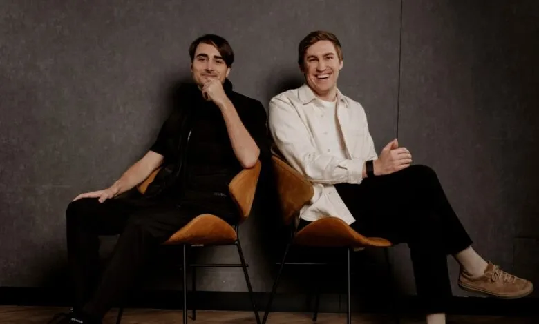 Two men, co-founders of ElevenLabs, sitting on chairs against a dark textured wall.