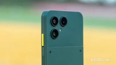 Close-up of the rear camera module of a dark green Fairphone with a yellow accent button.