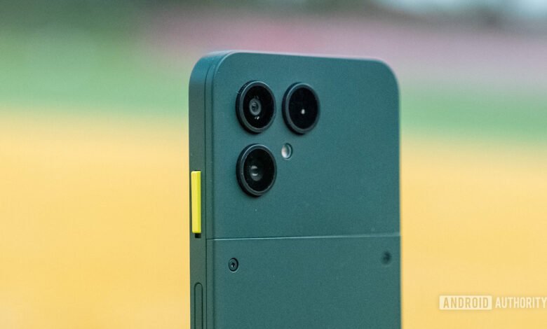 Close-up of the rear camera module of a dark green Fairphone with a yellow accent button.
