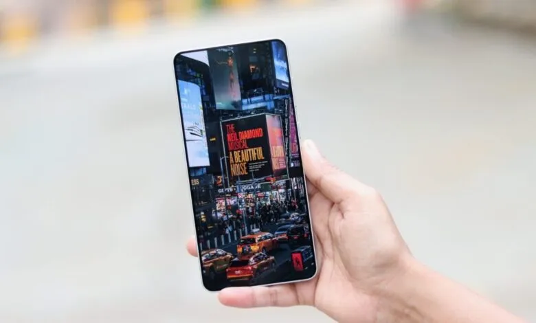 Hand holding a smartphone displaying a vibrant Times Square scene with billboards and traffic.