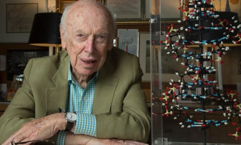 James Watson, co-discoverer of DNA, poses next to a DNA double helix model.