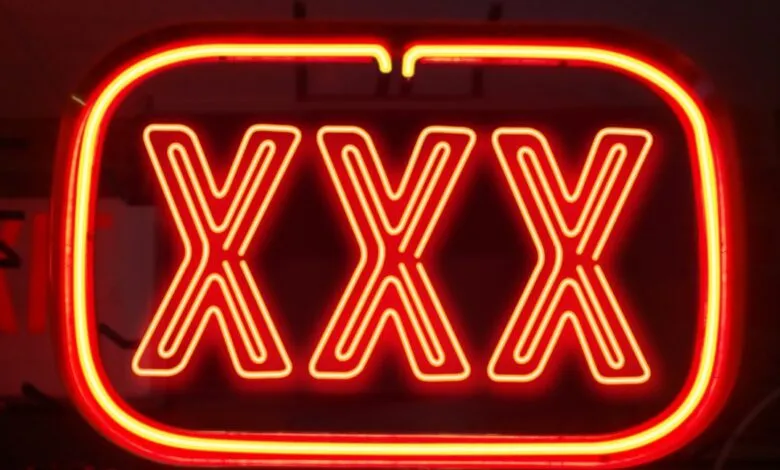 Close-up of a neon sign with three large 'X's in red and yellow.