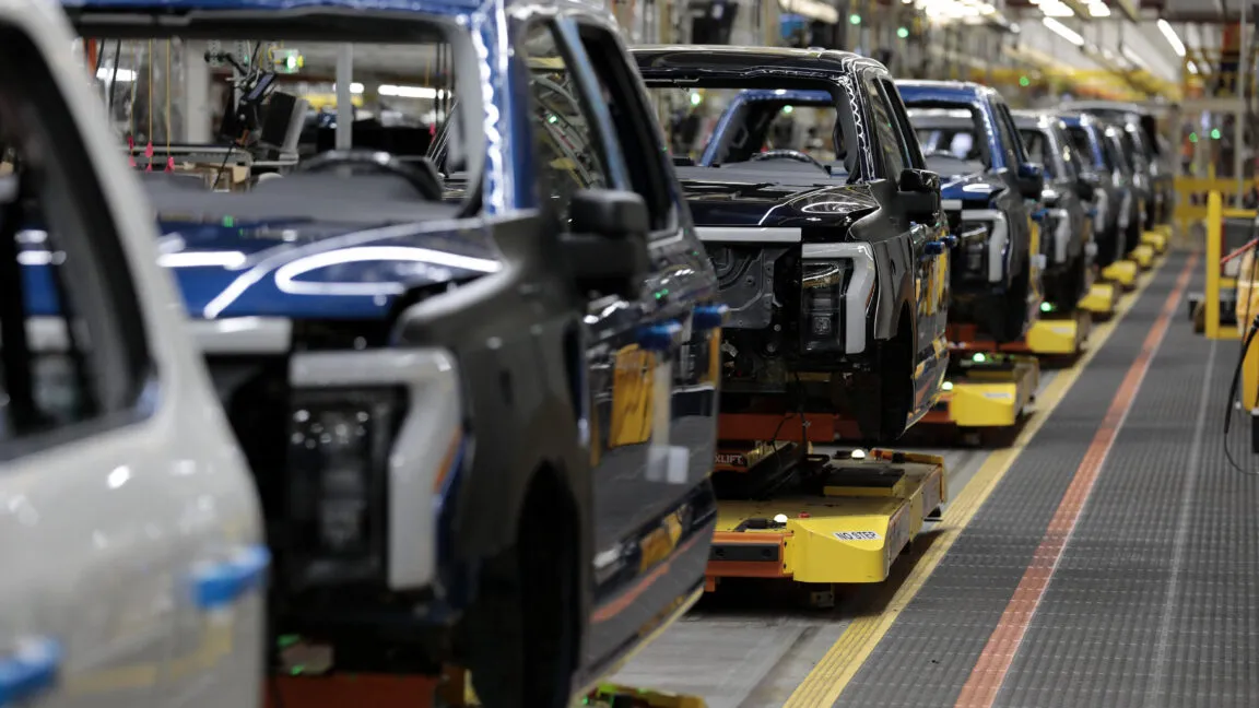 Ford F-150 Lightning electric trucks on an assembly line in a factory.