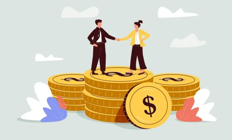 Business people shaking hands atop stacks of gold coins.