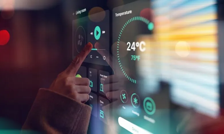 A person's finger touches a smart home control panel displaying temperature and living room settings.