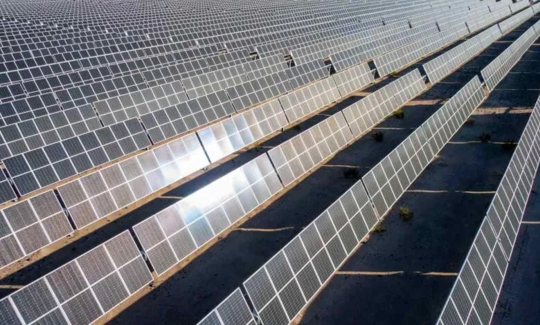 Aerial view of a vast solar farm with rows of photovoltaic panels stretching into the distance.