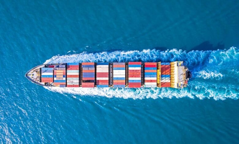 Aerial view of a large container ship moving through blue ocean water.