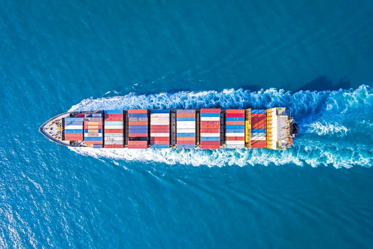 Aerial view of a large container ship moving through blue ocean water.