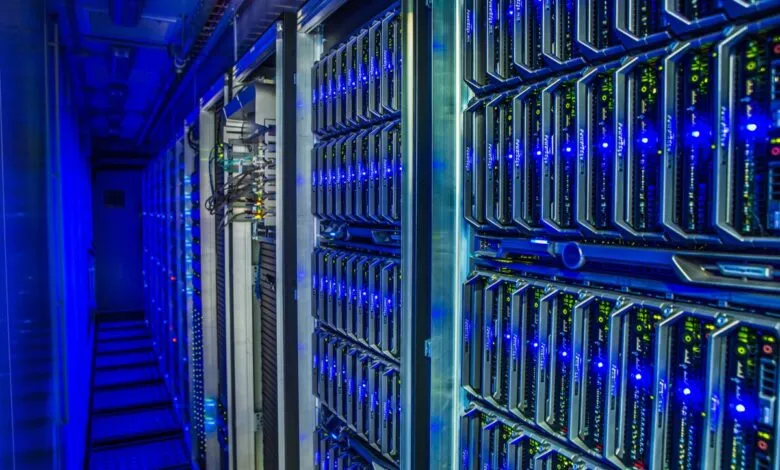 Rows of illuminated server racks in a data center with blue lighting.