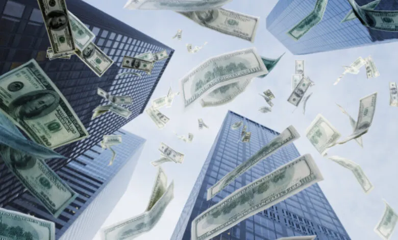 One hundred dollar bills raining down in front of modern skyscrapers.