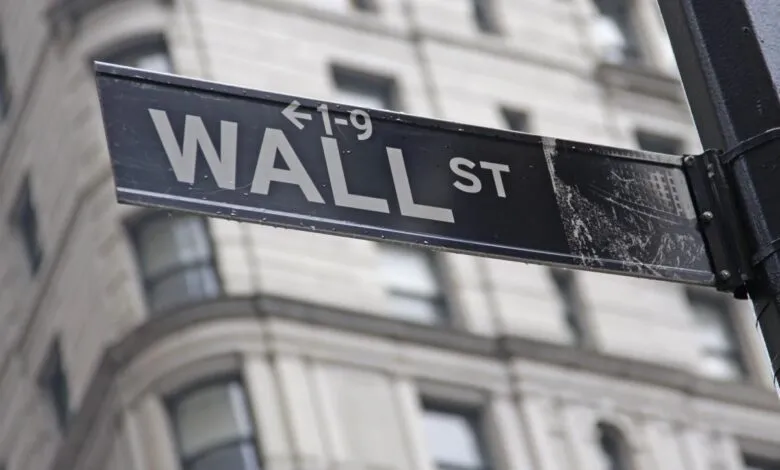 Wall Street sign in New York City with building in background.