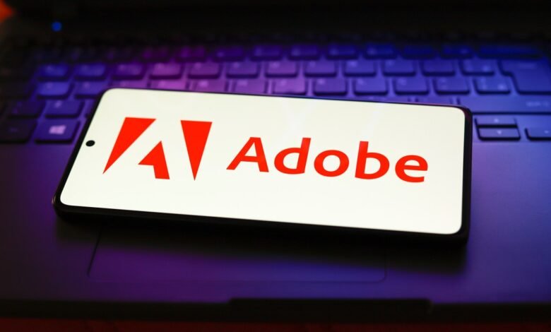 Smartphone displaying the Adobe logo and name on a laptop keyboard.