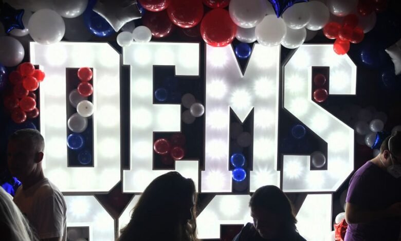 Large illuminated letters spelling 'DEMS' surrounded by red, white, and blue balloons.