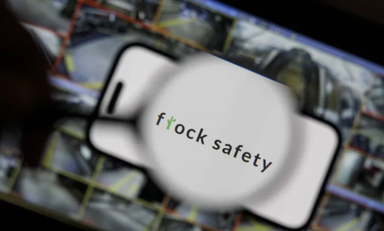Close-up of a smartphone displaying the Flock Safety logo over a grid of security camera feeds.