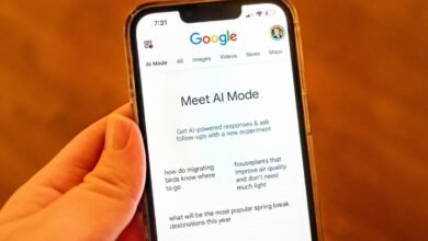 A hand holds a smartphone displaying Google's AI Mode interface.